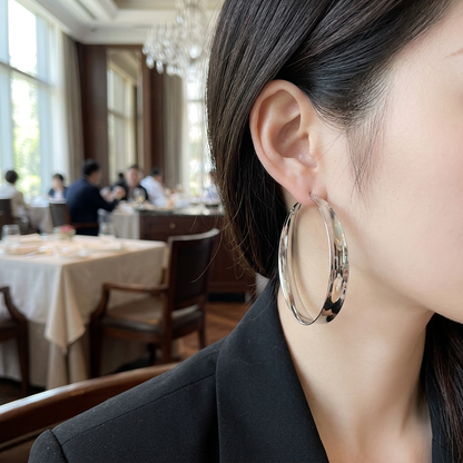 Duży szeroki kolczyk kółko w srebrnym kolorze na modelce w restauracji